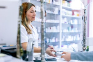 Woman pharmacist consulting customer at counter for prescription drugs or medicine at the pharmacy. Female doctor giving patient medical antibiotics at the pharmacy