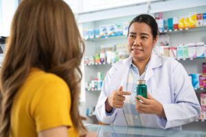 A pharmacist discussing medication with a customer in a pharmacy, highlighting pharmacy staffing challenges in providing personalized patient care.