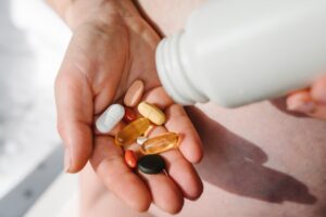 A hand holding a variety of pills and supplements, symbolizing expanding clinical services in independent pharmacies and their role in personalized patient care.